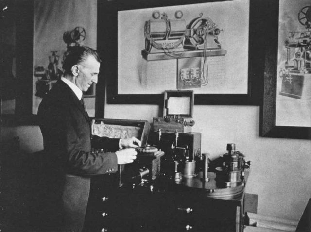 1916 की तस्वीर जिसमें निकोला टेस्ला अपने एक आविष्कार के साथ खड़े हैं।